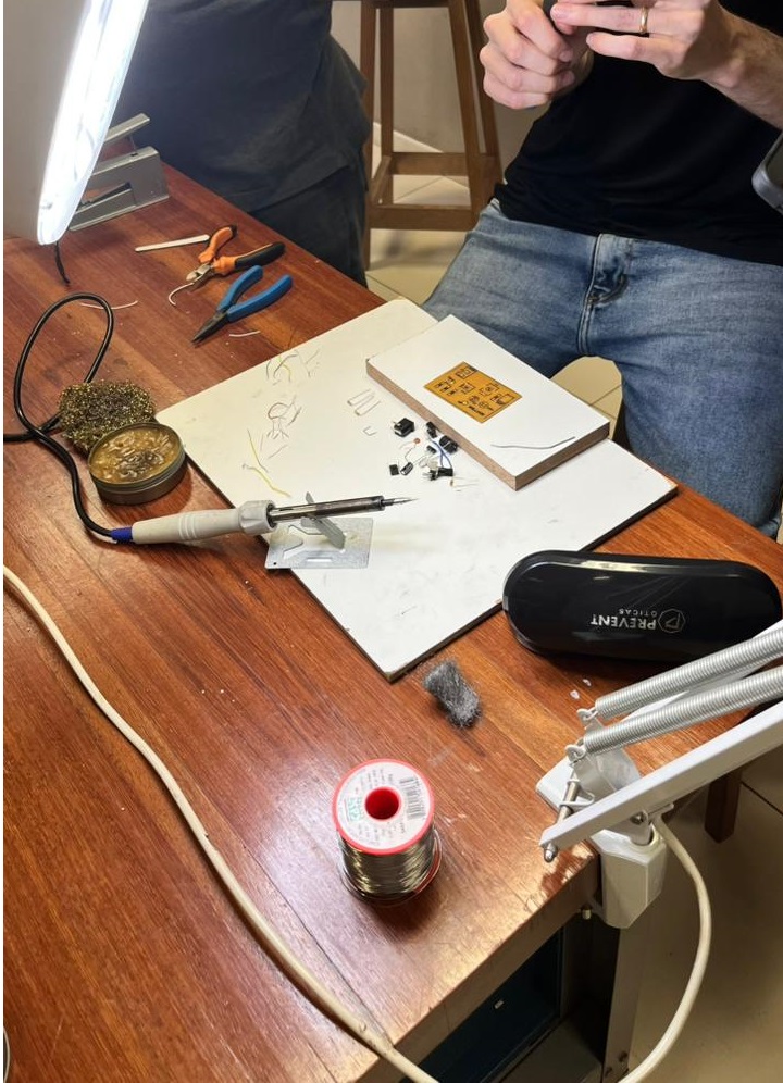 Bancada com ferro de solda, placa e componentes para montagem